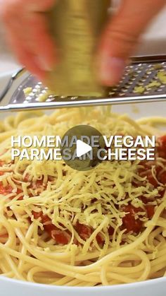 someone is adding parmesan cheese to a bowl of spaghetti