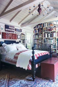 a bedroom with a bed, bookshelf and rugs on the floor in front of it