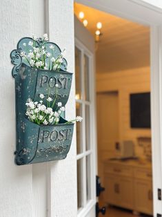 there is a sign that says post and flowers in the pot on the door handle