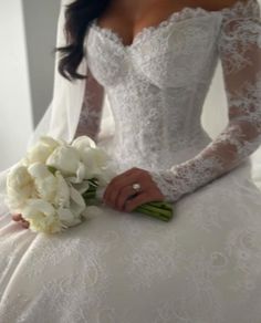 a woman in a wedding dress holding a bouquet of flowers