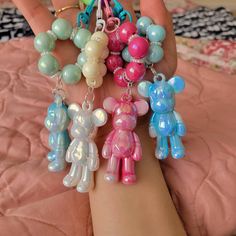 a person holding several different colored teddy bears on their arm with beads attached to them