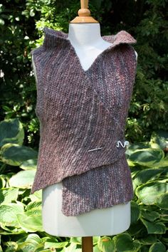 a knitted vest on a mannequin in front of some bushes and trees