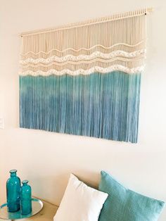 a blue vase sitting on top of a table next to a wall hanging over a bed