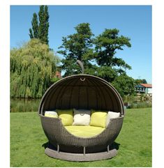 an outdoor swing chair with yellow pillows on it in the middle of a grassy area