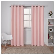 a white chair sitting in front of a window with pink curtains on top of it