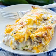 a white plate topped with an omelet covered in meat and cheese next to a fork