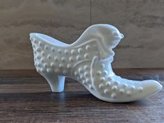 a white ceramic shoe sitting on top of a wooden table