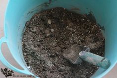 a blue bucket filled with dirt and a shovel