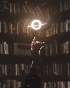 a person holding their hand up in front of a book shelf