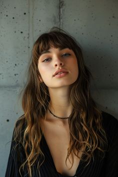 Woman with long wavy hair and fringe, wearing a dark blouse and choker, in front of a textured grey wall. Snape Face, Haircut Styles For Women, Best Haircuts, Chin Length Bob