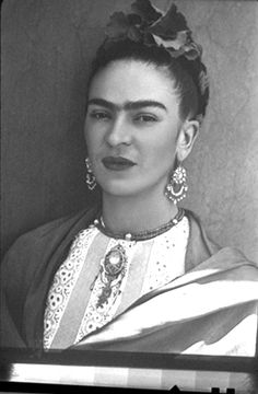 an old black and white photo of a woman with earrings on her head, looking at the camera