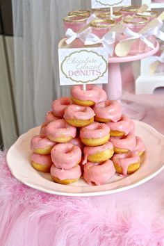 a plate full of pink donuts sitting on a table next to cupcakes