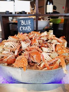 a large bowl filled with lots of crab on top of a table next to a sign that says blue crab