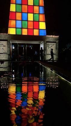 the reflection of people standing in front of a building with multicolored squares on it