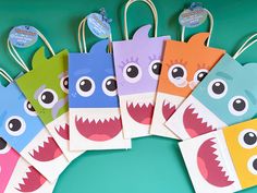 colorful paper bags with monster faces are on a green background and have tags attached to them