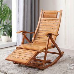 a wooden rocking chair sitting on top of a carpeted floor next to a potted plant