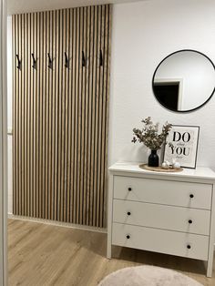 a white dresser sitting in front of a mirror on top of a wooden floor next to a wall