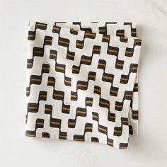 a black and white pattern with orange stripes on a table cloth that is folded in half