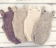 three knitted baby mittens sitting next to each other on a white wooden surface