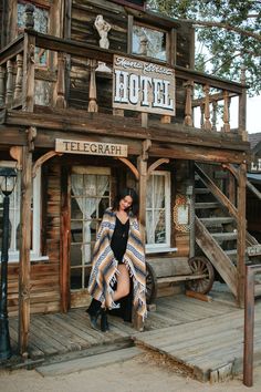 a woman standing in front of a wooden building