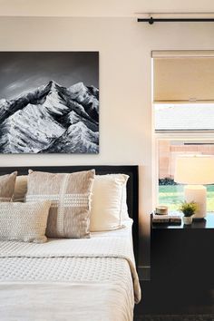 a bedroom with a large painting on the wall next to a bed and night stand