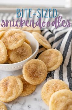 a white bowl filled with sugared cookies on top of a marble counter next to a striped towel