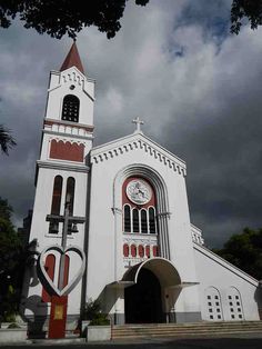 a large white church with a clock on it's side and stairs leading up to the entrance