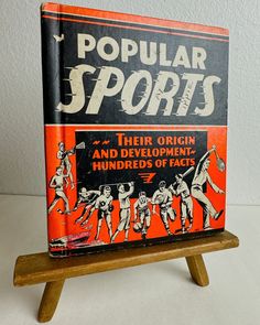 an orange and black book on a wooden stand with the title popular sports written in it