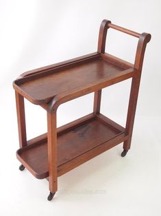 a wooden serving cart with two shelves on wheels