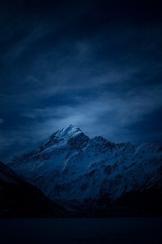 snow covered mountains under a cloudy sky at night