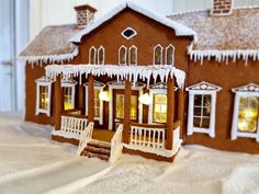 a gingerbread house with icing on the roof and windows is shown in front of snow covered ground