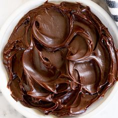 a white bowl filled with chocolate frosting on top of a table