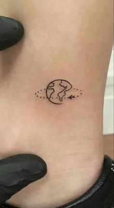 a small earth tattoo on the side of a woman's ribcage is shown