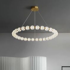 a modern chandelier hanging from the ceiling in a room with white walls and flooring