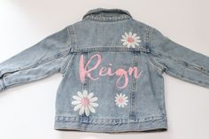 Custom Embroidered Denim Name Jacket With 3 Flowers!  Choose your thread color that'll be used for name and flower centers! Cream thread will be used for flower petals unless specified.  Old Navy Jackets *Runs small in my opinion Select Size: Toddler: 100% Cotton Light Denim Jackets 3-6 months 6-12 months 12-18 months 2T 3T 4T 5T Girls 95% Cotton, 5% Spandex  Medium Denim Jackets S (6/7) M (8) L (10/12) XL (14/16) Spring Blue Denim Jacket With Custom Embroidery, Pink Embroidered Cotton Denim Jacket, Spring Denim Outerwear With Custom Embroidery, Spring Denim Jacket With Custom Embroidery, Spring Denim Jacket With Custom Embroidery And Long Sleeves, Hand Painted Denim, Light Denim Jacket, Custom Denim Jacket, Embroidered Jean Jacket