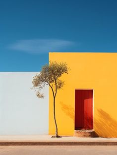 a lone tree in front of a yellow building with red door and window on the side