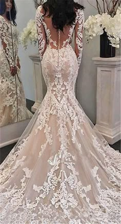 the back of a wedding dress with long sleeves and lace on it, in front of a mirror