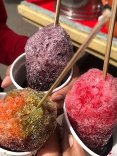 three different colored ice creams in small bowls with chop sticks sticking out of them