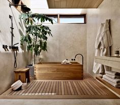 a large wooden bathtub sitting next to a plant on top of a table in front of a window