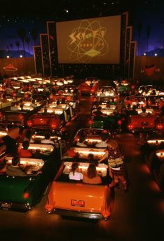 a large room filled with lots of cars in front of a projector screen at night