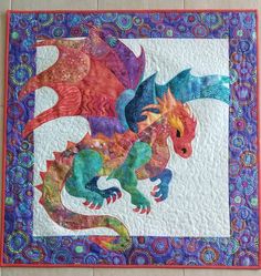 a quilted wall hanging with a colorful dragon on it