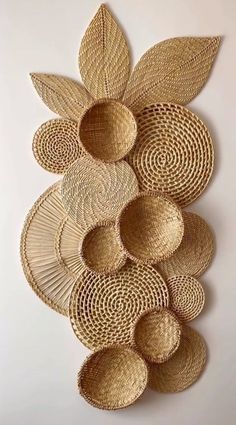 woven baskets are arranged in the shape of an abstract flower on a white wall with leaves