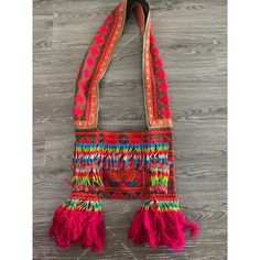 a red bag with tassels hanging on a wooden wall