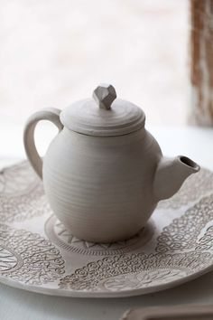 a white tea pot sitting on top of a plate