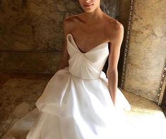 a woman in a white wedding dress posing for the camera