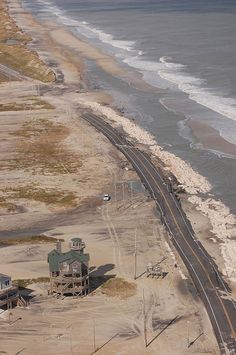 an aerial view of the beach and ocean with train tracks running along it's sides