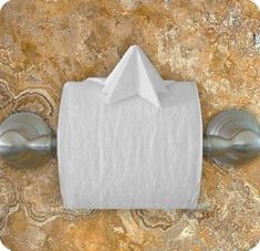 a roll of toilet paper sitting on top of a metal wall mounted holder with two napkins attached to it