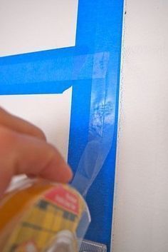 a person is painting the wall with blue tape and adhesive to protect it from scratches