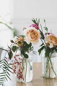 three vases filled with flowers on top of a wooden table