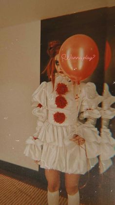 a girl in a white dress holding a red balloon